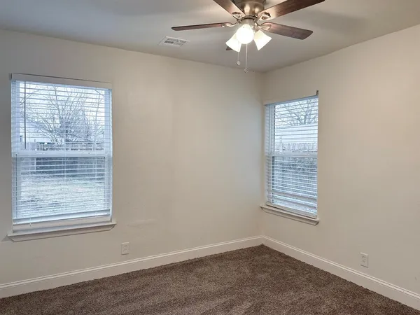 an empty room with windows and fan