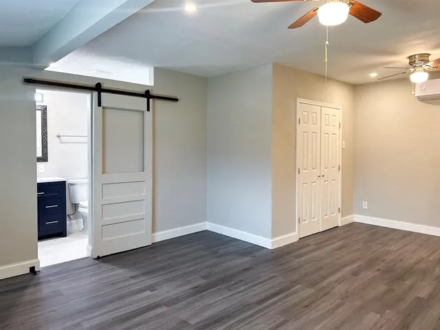 an empty room with wooden floor closet and windows