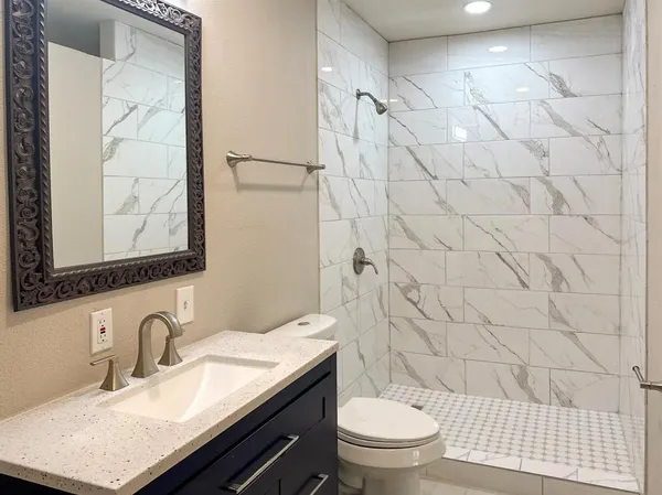 a bathroom with a granite countertop sink a toilet and a mirror