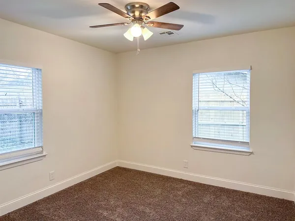 an empty room with windows and fan