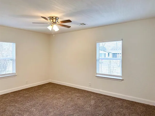 an empty room with windows and fan