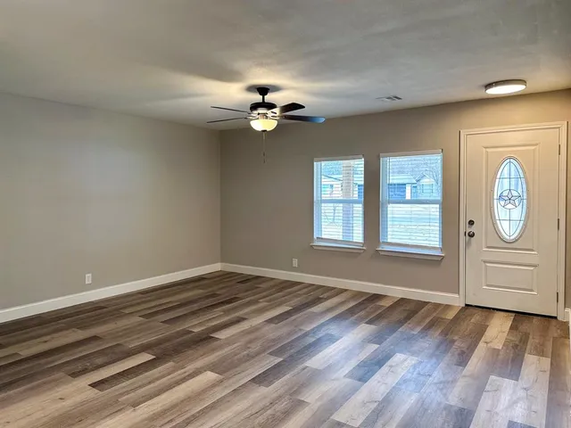 a view of an empty room with window and wooden floor
