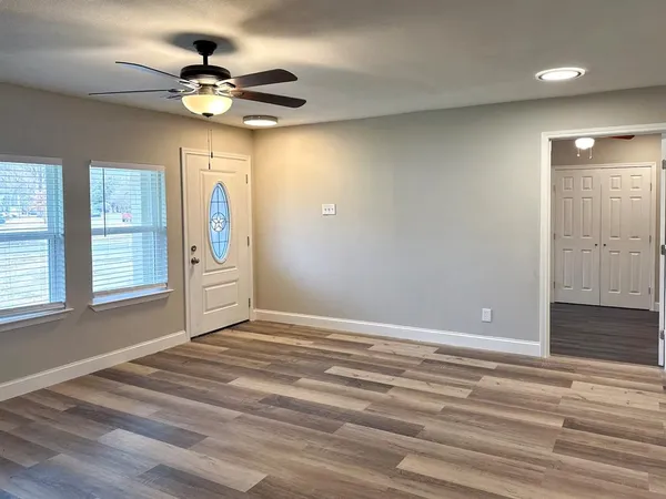 a view of an empty room with window and wooden floor