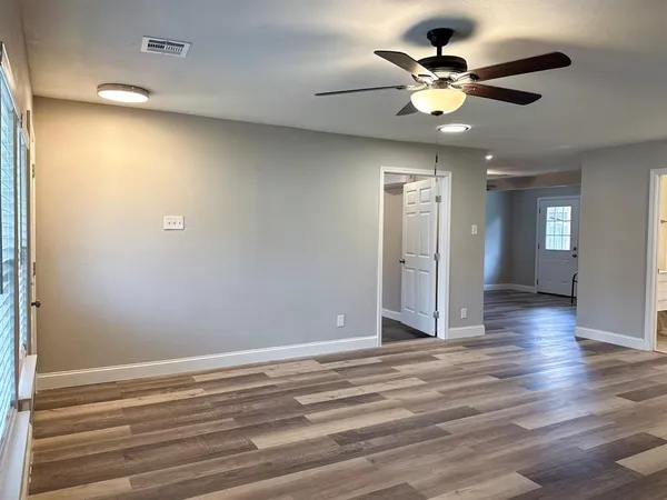 a view of an empty room with wooden floor and a window