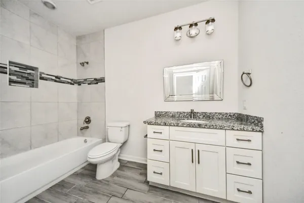 a bathroom with a granite countertop toilet a sink and bathtub