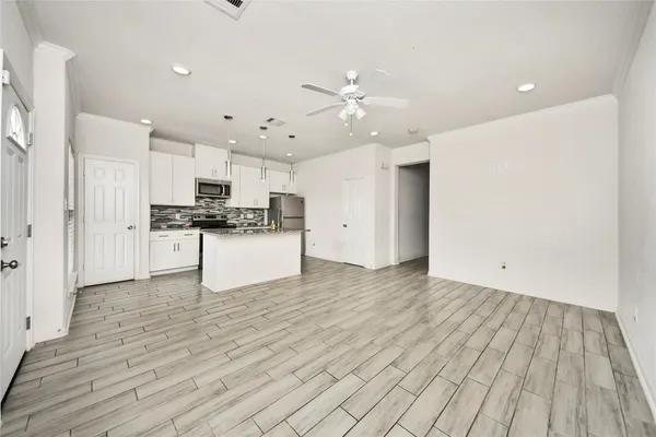a view of an empty room with kitchen wooden floor and window