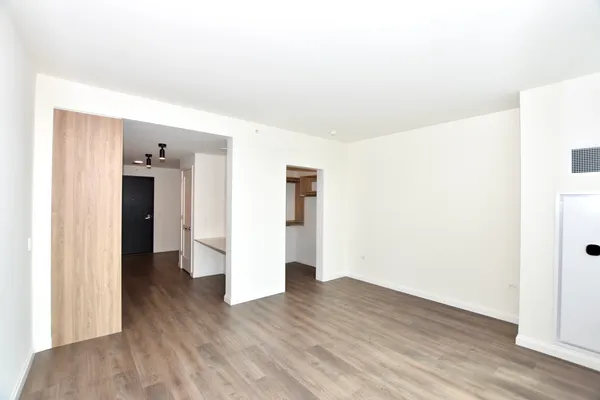 a view of an empty room with wooden floor and closet