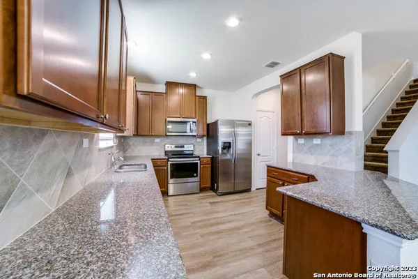 a kitchen with stainless steel appliances granite countertop a stove a sink and a refrigerator