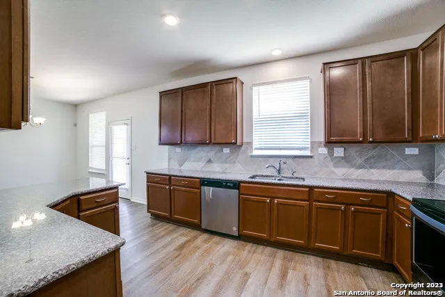 a kitchen with stainless steel appliances granite countertop wooden cabinets a sink and dishwasher