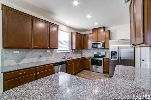 a kitchen with stainless steel appliances granite countertop a stove a sink and a refrigerator