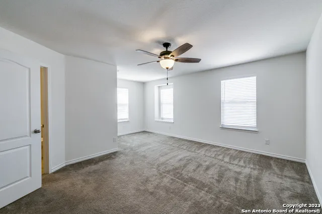 a view of an empty room with a ceiling fan and window