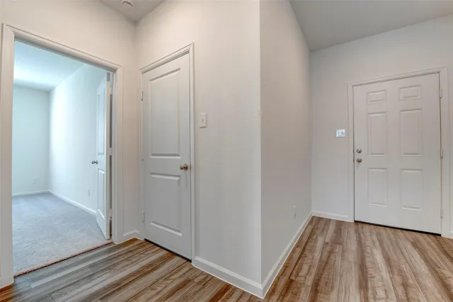 a view of a hallway with wooden floor and closet area