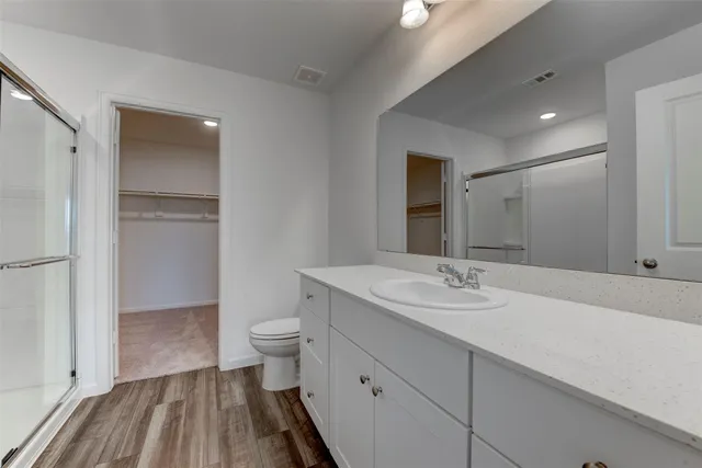 a bathroom with a sink a toilet a shower and a large mirror