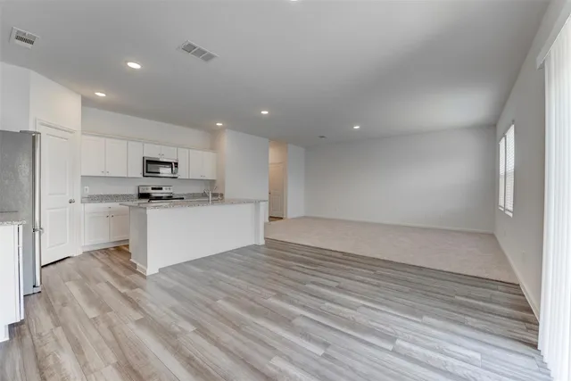 a view of kitchen with granite countertop cabinets and refrigerator