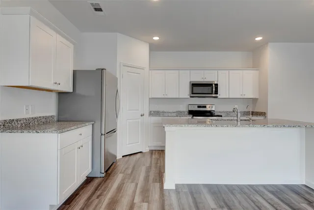a kitchen with granite countertop a refrigerator stove top oven and sink