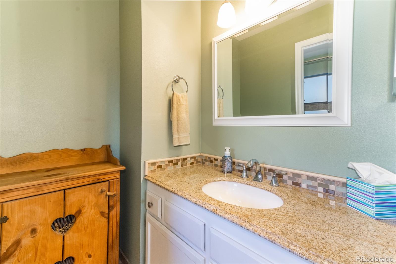 9164 Bitterweed Court Highlands Ranch, CO 80126 - Photo 14 of 27 a bathroom with a granite countertop sink and a mirror