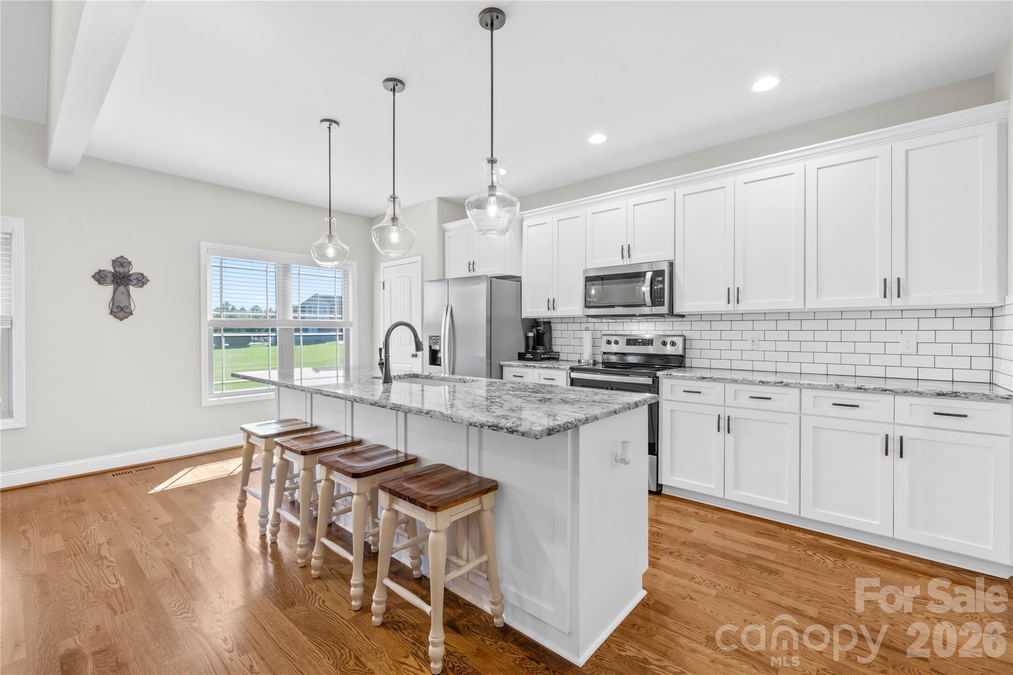 895 Oak Ridge Farms Circle Newton, NC 28658 - Photo 24 of 43 a kitchen with stainless steel appliances granite countertop a stove a sink a microwave a dining table and chairs with wooden floor