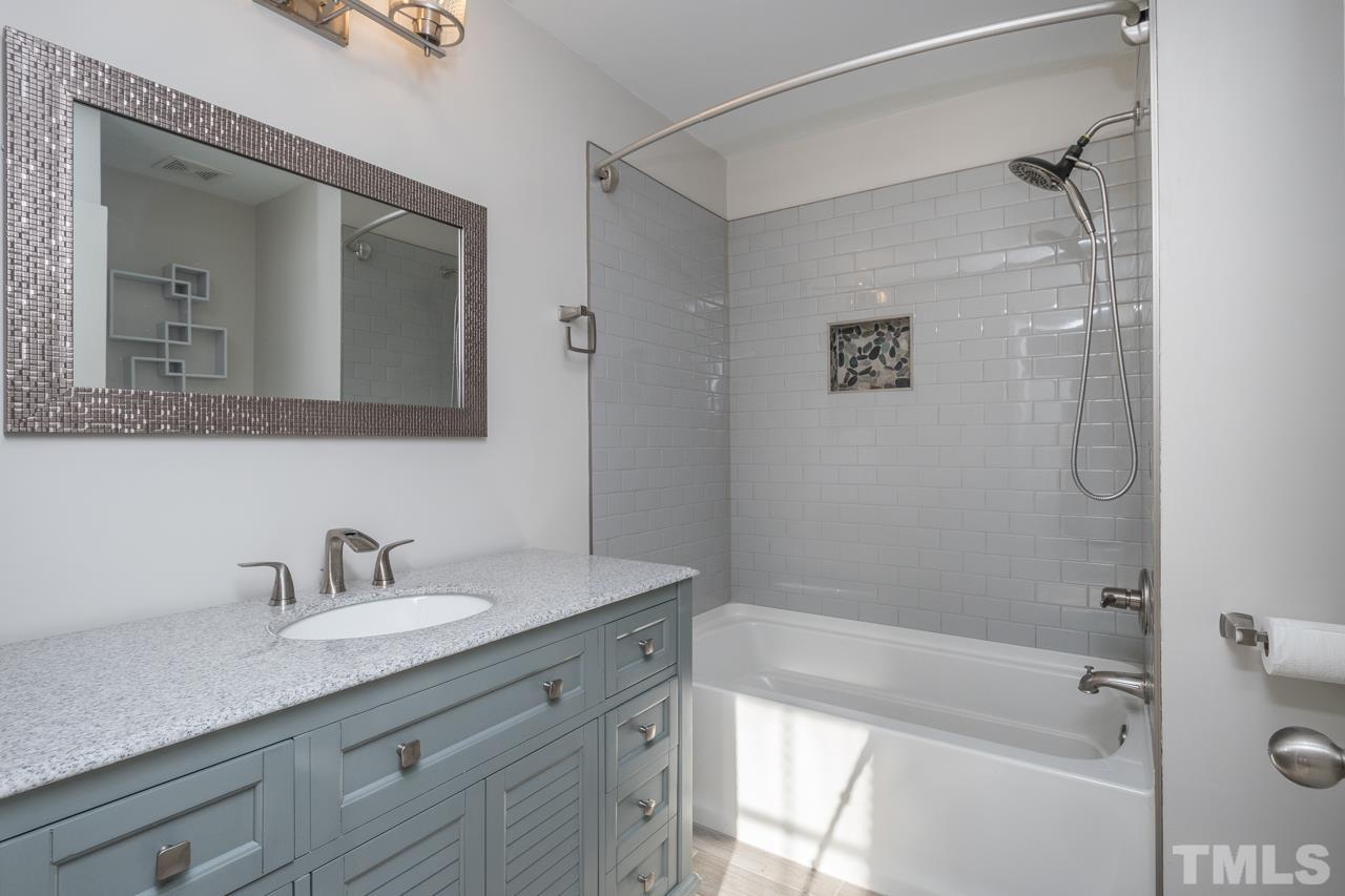 7244 Janston Drive Raleigh, NC 27613 - Photo 14 of 19 a bathroom with a granite countertop sink a mirror a shower and a bathtub