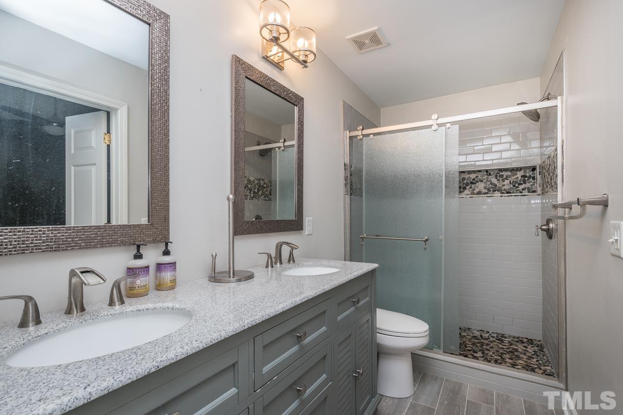 7244 Janston Drive Raleigh, NC 27613 - Photo 10 of 19 a bathroom with a granite countertop sink toilet a large mirror a shower and a mirror