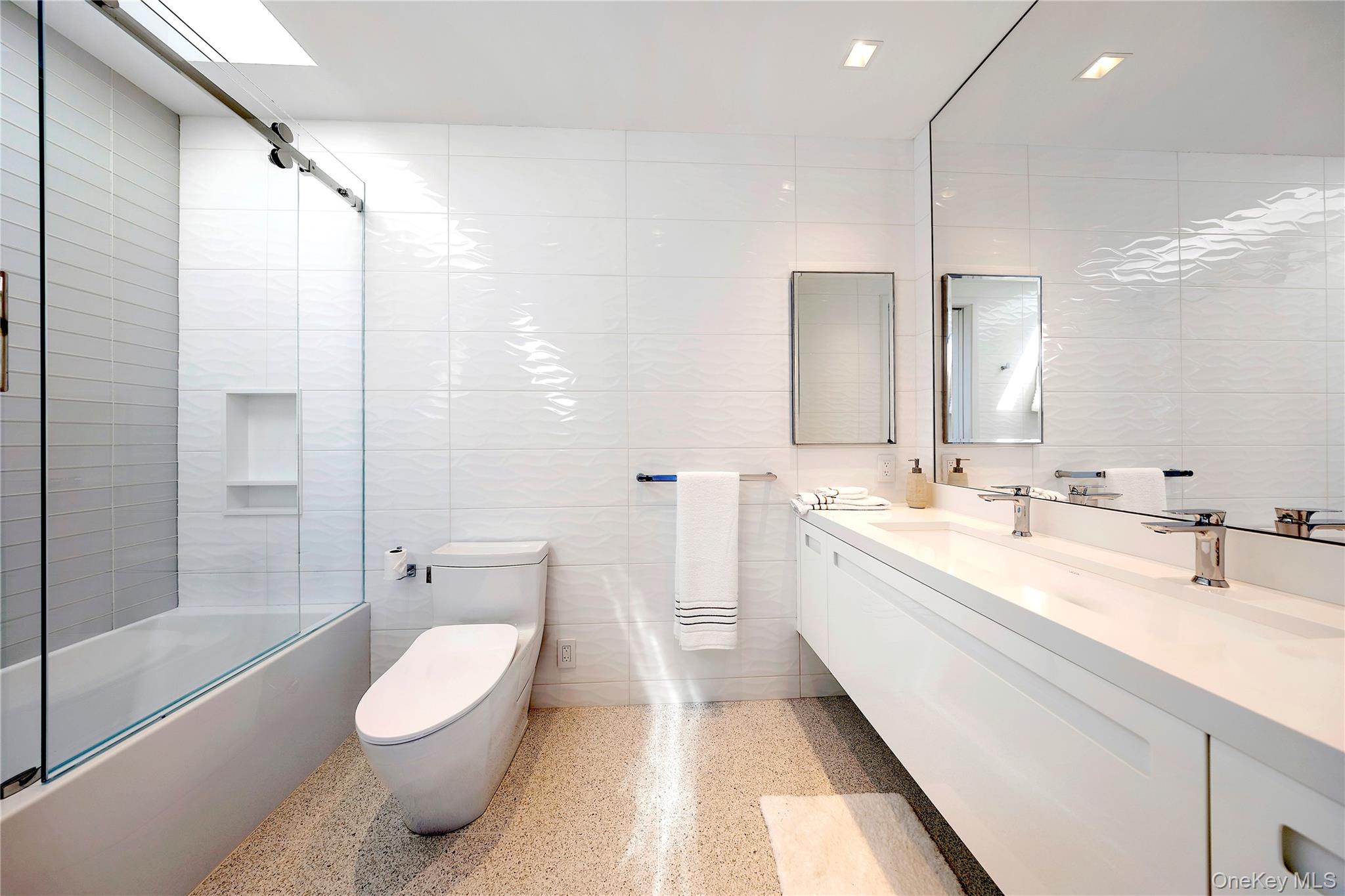 345 Dune Road Westhampton Beach, NY 11978 - Photo 24 of 34 a spacious bathroom with a double vanity sink toilet mirror and bathtub