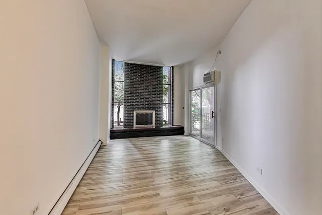a view of empty room with wooden floor and fireplace