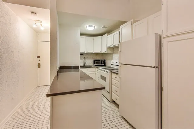 a kitchen with a refrigerator a stove top oven and white walls
