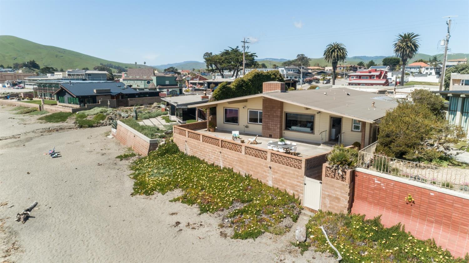 8 Ocean Front Lane Cayucos, CA 93430 - Photo 26 of 32 a view of a white house with a yard and lawn chairs under an umbrella