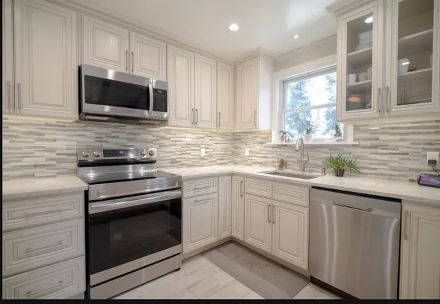 a kitchen with granite countertop white cabinets stainless steel appliances and a sink