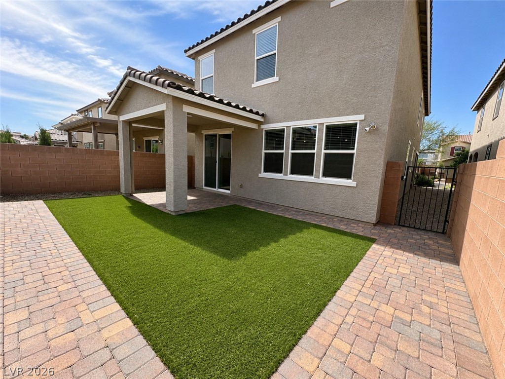 8768 Rio Andir Avenue Las Vegas, NV 89148 - Photo 9 of 9 A well-maintained paved walkway encircles a neat artificial turf yard, leading to a covered patio ideal for outdoor enjoyment.