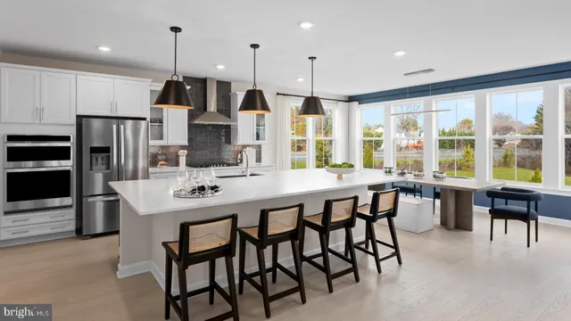 a kitchen with stainless steel appliances kitchen island granite countertop a stove a refrigerator a sink a dining table and chairs with wooden floor