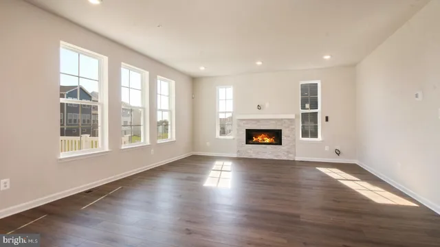 an empty room with wooden floor fireplace and windows