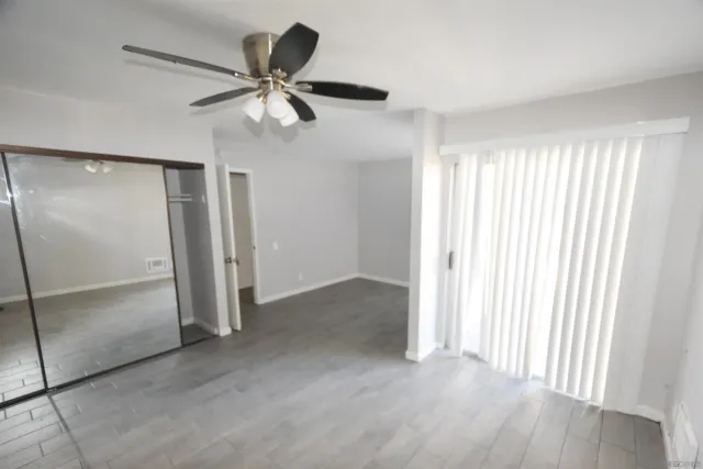 a view of empty room with wooden floor and ceiling fan