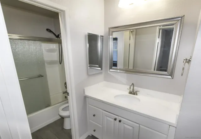a bathroom with a sink a toilet a mirror and shower