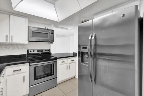 a kitchen with granite countertop white cabinets and a sink