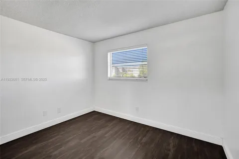 an empty room with wooden floor closet and windows