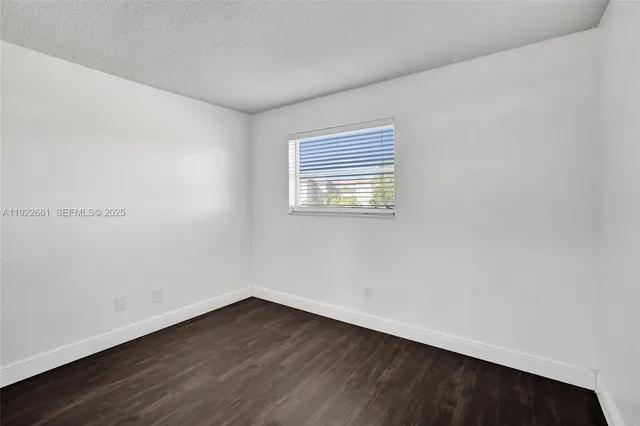 an empty room with wooden floor closet and windows