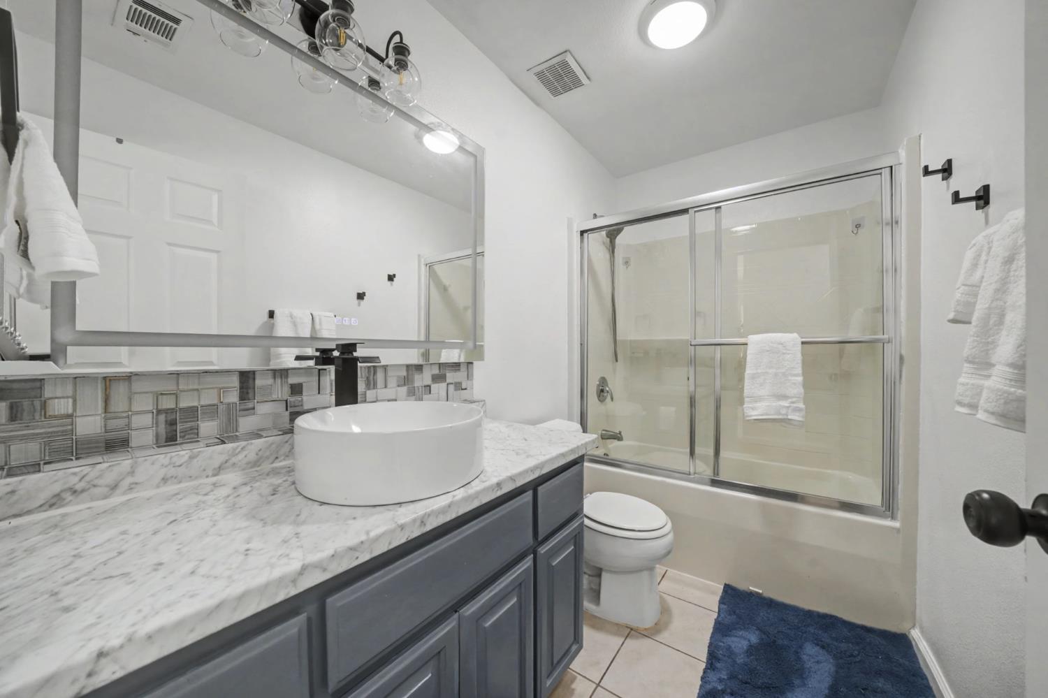 7761 Jenny Lind Road Valley Springs, CA 95252 - Photo 16 of 35 a bathroom with a granite countertop sink a toilet a mirror and shower