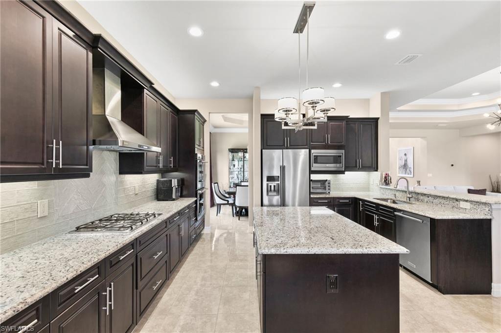 4370 Caldera Circle Naples, FL 34119 - Photo 4 of 35 a kitchen with kitchen island granite countertop a sink stove and refrigerator