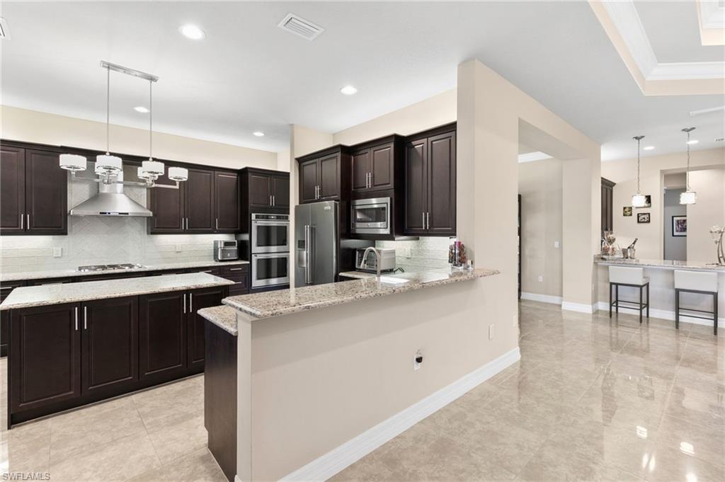 4370 Caldera Circle Naples, FL 34119 - Photo 6 of 35 a kitchen with stainless steel appliances kitchen island granite countertop a sink and cabinets