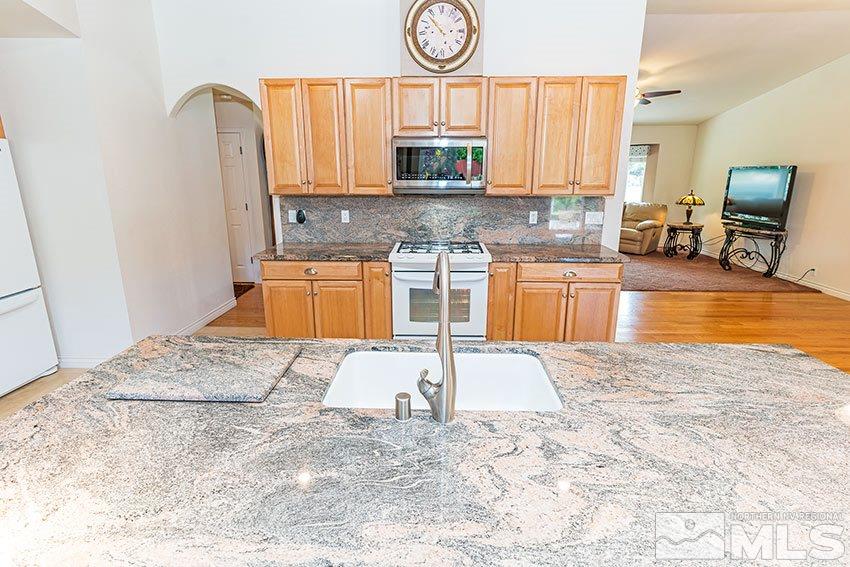 14345 Chamy Drive Reno, NV 89521 - Photo 3 of 15 a kitchen with stainless steel appliances granite countertop a stove a sink and a microwave