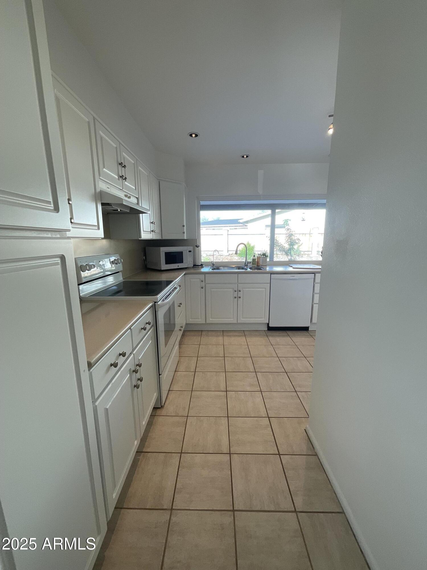 6802 North 26th Street Phoenix, AZ 85016 - Photo 13 of 39 a kitchen with a sink a stove top oven and cabinets