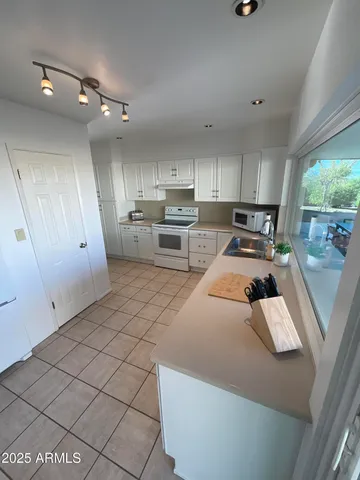 a kitchen with granite countertop a sink a stove a refrigerator and cabinets