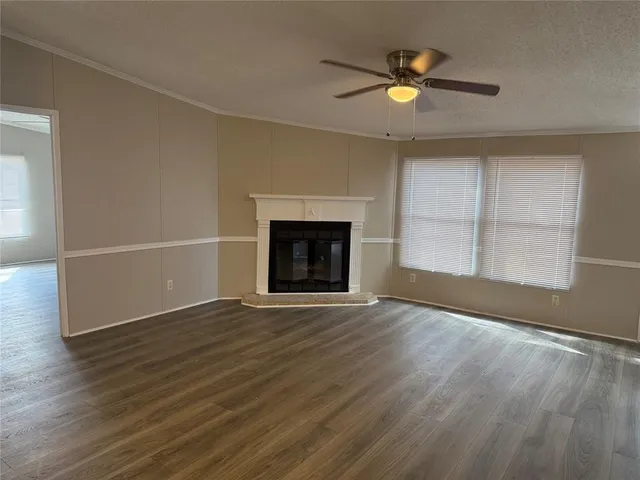 an empty room with wooden floor fireplace and windows