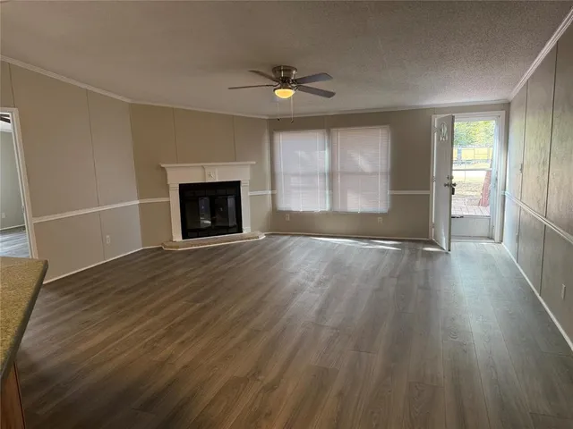 an empty room with wooden floor fireplace and windows