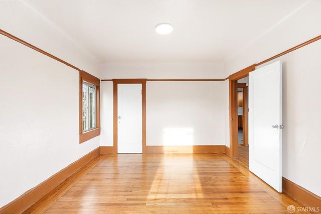 a view of an empty room with a window and wooden floor
