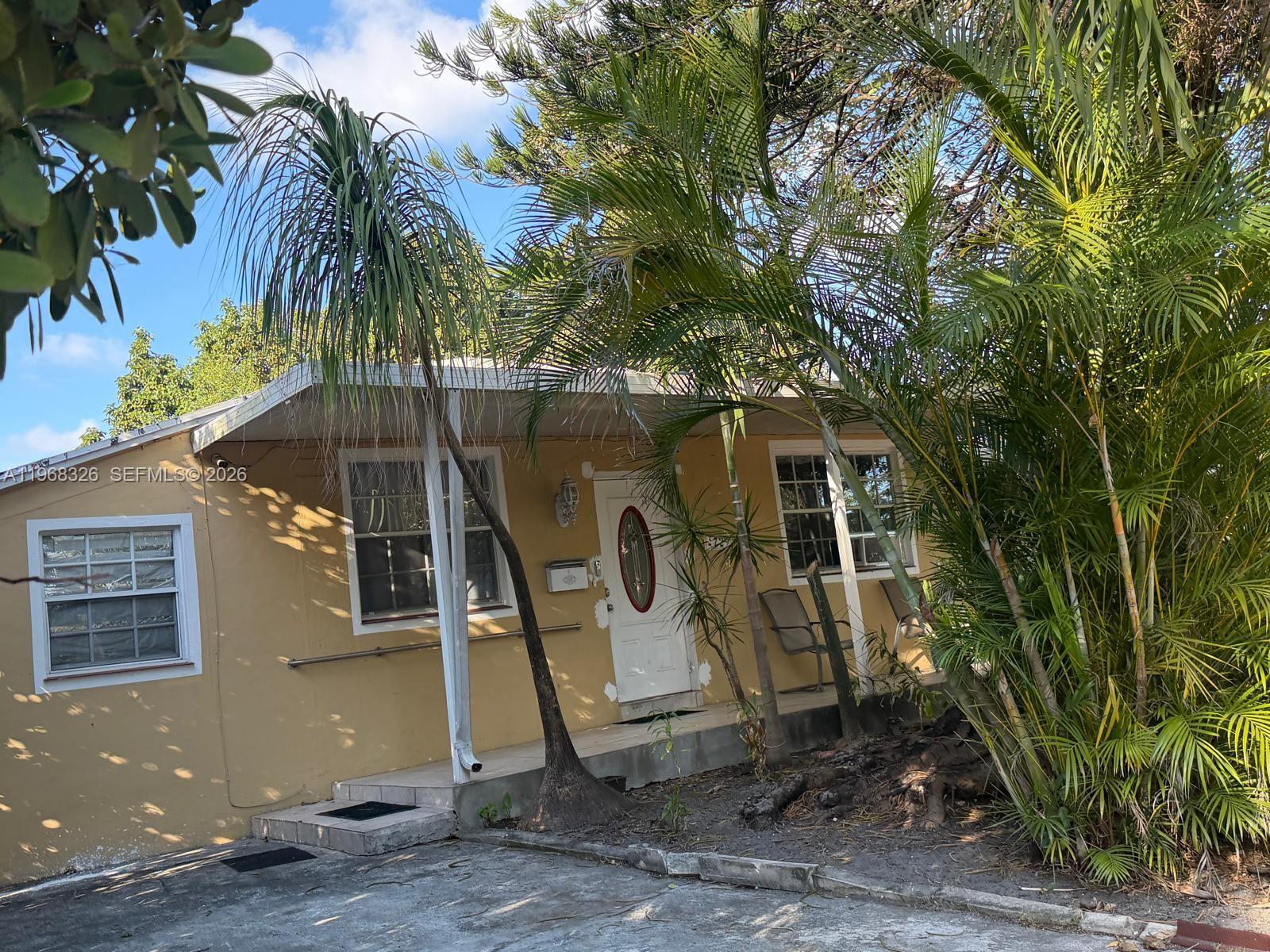 4729 Southwest 4th Street Miami, FL 33134 - Photo 3 of 4 a view of a small white house with a large tree and next to a yard