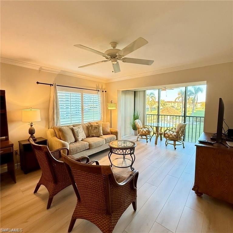57 High Point Circle West, Unit 201 Naples, FL 34103 - Photo 4 of 18 a living room with furniture a flat screen tv and a large window