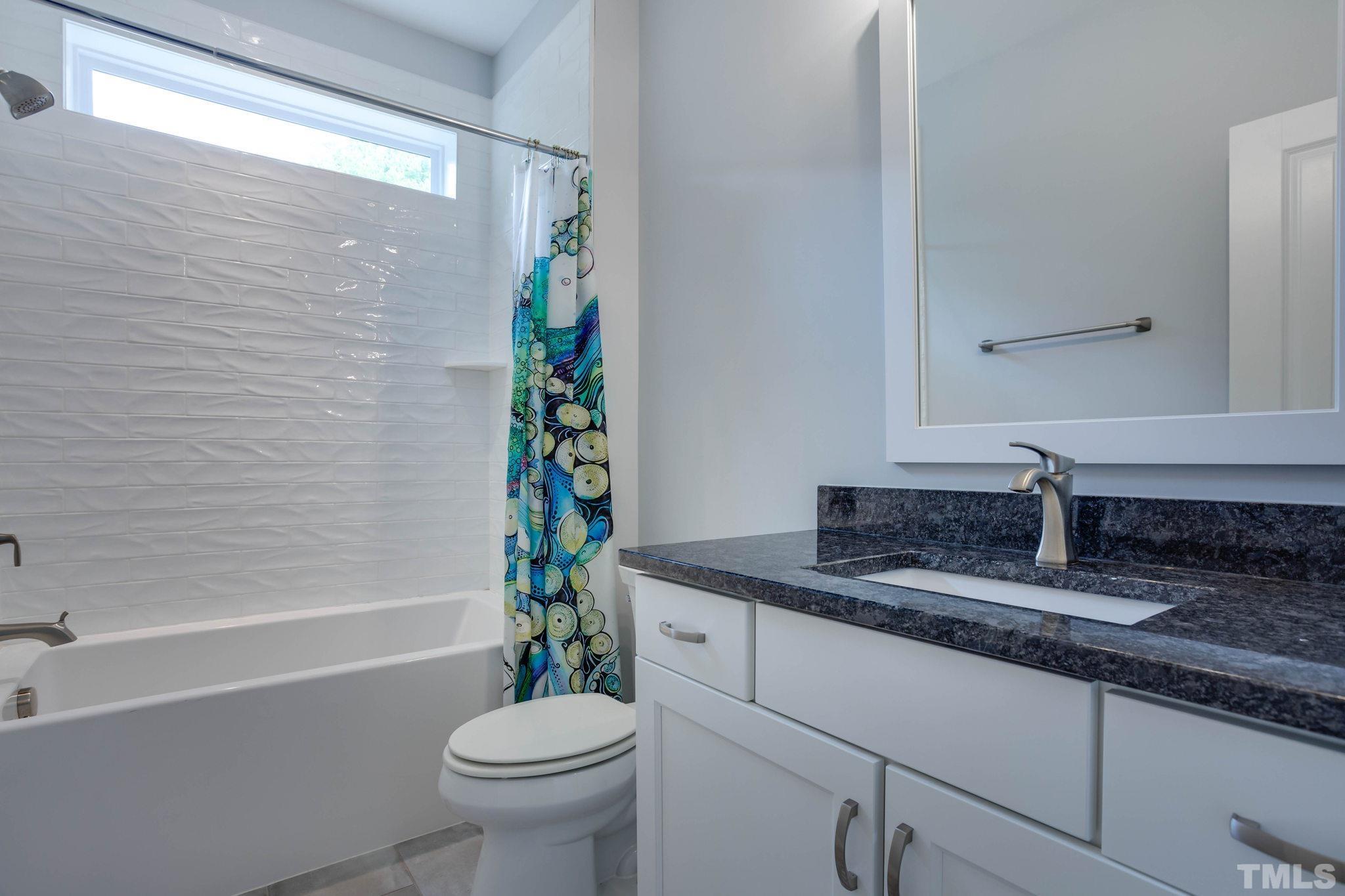 1702 Bickett Boulevard Raleigh, NC 27608 - Photo 26 of 41 a bathroom with a granite countertop sink a toilet a mirror and bathtub