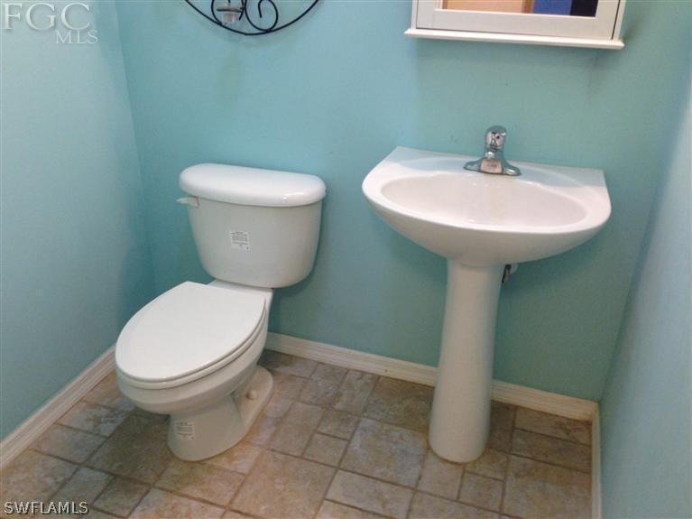 348 Rancho Avenue Lehigh Acres, FL 33974 - Photo 6 of 10 a bathroom with a toilet sink and mirror
