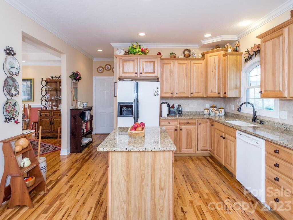 264 Hazel Brook Road Marshall, NC 28753 - Photo 22 of 47 a kitchen with stainless steel appliances kitchen island granite countertop a refrigerator a sink dishwasher and white cabinets with wooden floor
